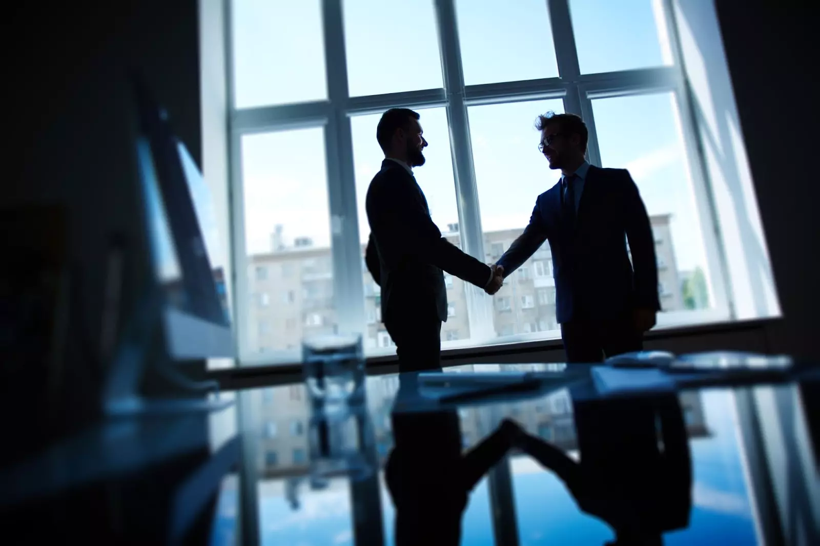 Two men shake hands after renegotiating the selling price on a real estate property.